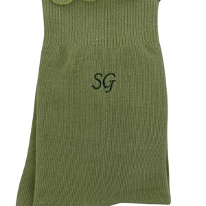 May include: Green ankle socks with a frilled top and the letters "SG" embroidered on the front.