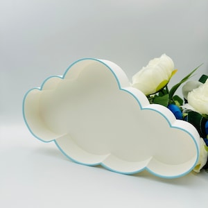 May include: A white cloud-shaped tray with a light blue rim. The tray is empty and is sitting on a white surface.
