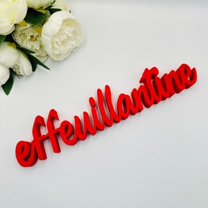 May include: Red wooden sign with the word "effeuillantine" written in a cursive font.