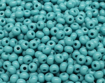 Può includere: Primo piano di una grande quantità di perline di rocaille blu turchese. Le perline sono piccole e rotonde, con un foro al centro. Sono perfette per la creazione di gioielli o altri progetti di artigianato.