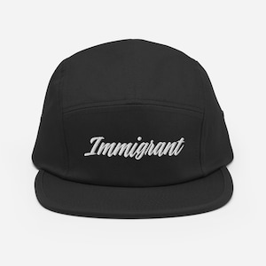May include: Black five-panel cap with a flat brim. The word "Immigrant" is embroidered in white script across the front. The cap is made of a durable fabric and has a classic, casual style.