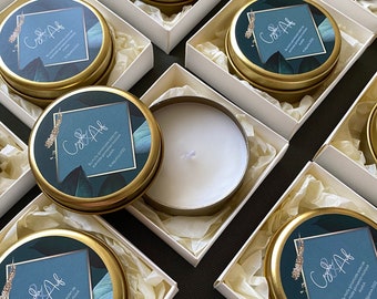 May include: A collection of small, round, gold-coloured tins with white lids. Each tin has a blue and green design with the text "Co&Af" and the date "18. April 2022".