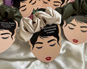 May include: Assortment of five colorful satin scrunchies with a printed card featuring a woman's face and the text "Asli'nin Kınası Kafana tokadan başka bir şey takma".