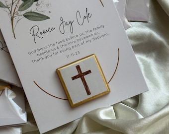 Könnte beinhalten: Eine weiße Karte mit goldenen Verzierungen und einem kleinen goldenen Rahmen, in dem sich ein braunes Holzkreuz befindet. Die Karte trägt den Text "Romeo Jay Cole" und "Gott segne das Essen, das vor uns steht, die Familie, die uns umgibt, und die Liebe, die uns verbindet. Danke, dass du Teil meiner Taufe warst. 11-11-23".