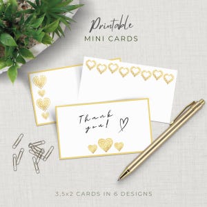 Può includere: Mini biglietti bianchi con disegni a cuore dorati e bordi dorati. Un biglietto recita "Thank you!" con un simbolo a cuore. Sono presenti anche una penna dorata e delle graffette. Il testo "Printable Mini Cards" è in alto. I biglietti misurano 8,9 x 5,1 cm.