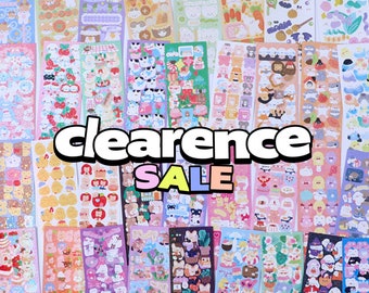 May include: A collection of colorful sticker sheets featuring cute cartoon animals, food, and other designs. The sticker sheets are arranged in rows and columns, and the text "clearance sale" is superimposed over the image.