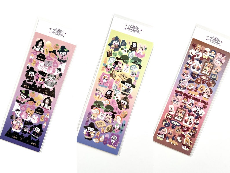 May include: Three sticker sheets with colorful illustrations of cartoon characters, including witches, cats, and food items. The stickers are packaged in clear plastic sleeves with the text "Wear & Decor" at the top.