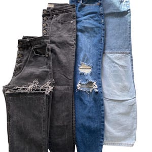 Peut inclure: Une collection de quatre pantalons en jean. Deux paires sont noires avec des fermetures à boutons et des ourlets effilochés. Une paire est bleu foncé avec des déchirures aux genoux et un ourlet brut. Une paire est bleu clair avec une couture.