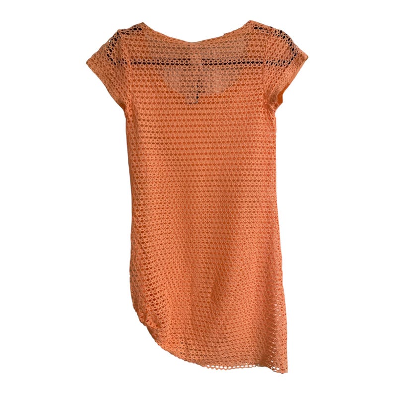 May include: A short-sleeved, peach-colored top featuring an open-knit, mesh-like crochet pattern throughout. The garment has a rounded neckline and a slightly asymmetrical hemline, constructed from a lightweight, semi-sheer textile material.