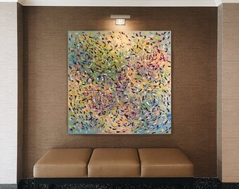 May include: Abstract painting with a swirling pattern of colorful dots and dashes on a light blue background. The painting is framed and hanging on a brown wall above a brown leather bench.