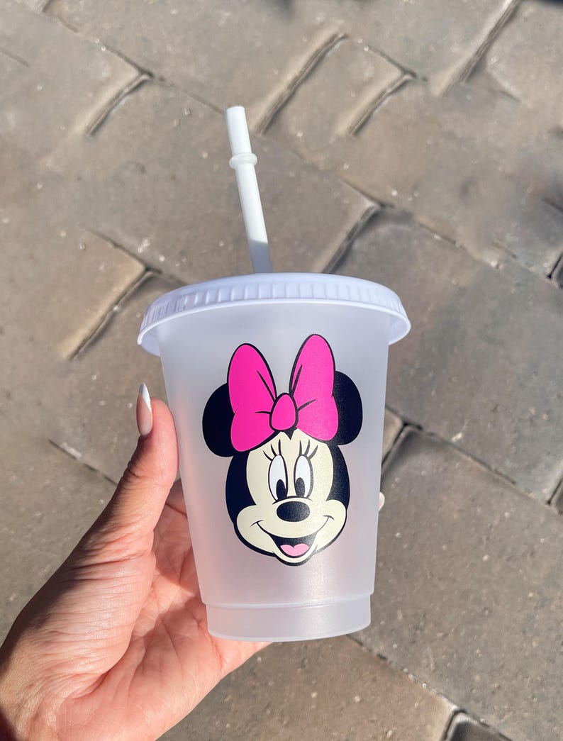 Puede incluir: Un vaso de pl&aacute;stico transparente con tapa y pajita blancas. El vaso presenta un gr&aacute;fico de Minnie Mouse con un lazo rosa. La taza est&aacute; dise&ntilde;ada para bebidas fr&iacute;as.