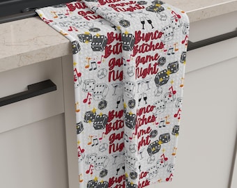 Peut inclure: Serviette de cuisine blanche avec un motif répété noir et rouge de dés, de notes de musique et le texte "Bunco Bitches Game Night".