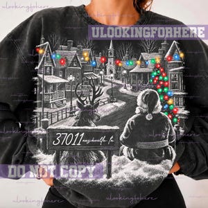 May include: A black acid-wash sweatshirt featuring a graphic of a snowy town at night with a reindeer and a person in a Santa suit sitting on a bench. The sign on the bench reads 37011 nashville tn. Colorful string lights hang above.