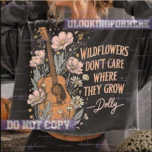 Può includere: Una felpa grigio antracite a maniche lunghe con la grafica di una chitarra acustica circondata da fiori di campo rosa e bianchi. Il testo recita: WILDFLOWERS DON'T CARE WHERE THEY GROW —Dolly. Il capo presenta un orlo corto.
