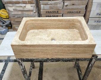 May include: A rectangular stone sink with a light brown color and a smooth, textured surface. The sink is sitting on a black metal stand with a rectangular frame.