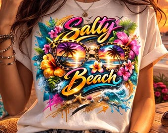 Könnte beinhalten: Weißes T-Shirt mit einem farbenfrohen Aufdruck "Salty Beach". Das Design zeigt eine Sonnenbrille mit einer Strandszene, umgeben von Blumen und Wellen. Die Person trägt Jeansshorts und Schmuck.