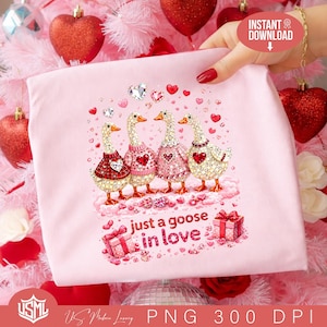 Puede incluir: Una camiseta rosa claro con cuatro gansos con suéteres decorativos, corazones y el texto "just a goose in love". Los gansos están sobre una nube con cajas de regalo y detalles de corazón. La imagen tiene un tema de San Valentín.