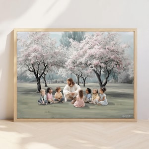 Op de afbeelding: Een ingelijste wandkunstprint met een centrale figuur met lang haar en een baard in een wit gewaad, zittend op de grond omringd door zeven diverse kinderen in een park met grote bomen met lichtroze bloesems in volle bloei.