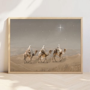 Könnte beinhalten: Gerahmter Druck, der drei Figuren auf Kamelen zeigt, die eine Wüstenlandschaft unter einem Sternenhimmel durchqueren. Die Figuren tragen weiße Gewänder, und ein heller Stern leuchtet über ihnen. Das Kunstwerk ist in gedämpften Erdtönen gehalten.