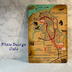 May include: A vintage map of Fort Wilderness Campground Resort at Bay Lake, Florida. The map shows the layout of the campground, including the campsites, trails, and amenities. The map is printed on a brown paper background with green, red, and blue accents. The text on the map includes "Fort Wilderness Campground Resort", "Bay Lake", "Trading Post", "New Campsite Loops", "Legend", "Track", "Depot", "Water", "Operating Path", "3.46 Miles", "River Country Transport Period", "May 1976 - Summer 1977", and "Vesta Boulevard".