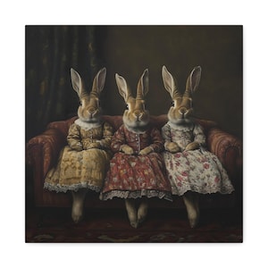 May include: A canvas print featuring three anthropomorphic rabbits seated on a red sofa. Each rabbit wears a vintage dress in shades of yellow, red, and floral patterns. The background is a dark, moody interior.