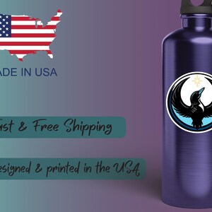 May include: A dark blue water bottle with a black and white graphic of a bird with outstretched wings and a star. The bottle has a black cap and a silver carabiner clip. The image also includes the text "Made in USA".