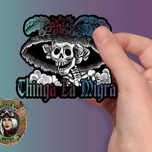 May include: A black and white sticker featuring a skeleton wearing a large hat with floral accents. The text "Chinga La Migra" is displayed below the skeleton. A smaller sticker with a woman in goggles is in the lower left corner.