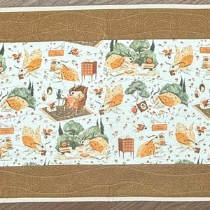 May include: A brown and white table runner with a repeating pattern of birds, trees, and houses. The pattern is on a white background with a brown border.