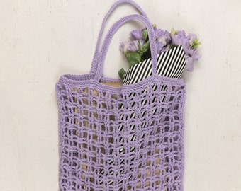 May include: A lavender crochet tote bag with a bouquet of purple flowers wrapped in black and white striped paper.