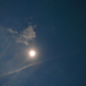 May include: A bright, white sun shining through a light blue sky with wispy white clouds.