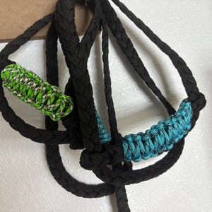 May include: A black braided rope with two green and white and blue and white braided rope accents.