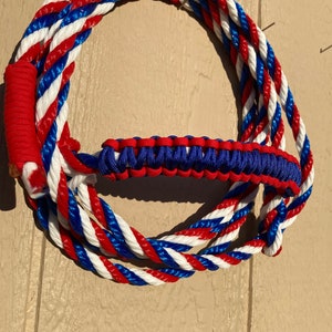 May include: A red, white, and blue braided rope with a matching braided handle. The rope is coiled into a circle.