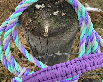 May include: A purple braided rope with a gray and teal rope wrapped around it. The rope is tied around a wooden post.