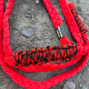 May include: Red braided rope with a black and red camouflage pattern. The rope has a tag that says "Cabin Creek Halters".