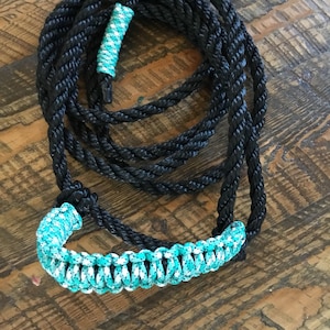May include: Black and turquoise braided rope halter with a turquoise and white braided handle.