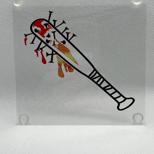 May include: A clear acrylic square featuring a graphic of a black baseball bat with spikes and blood-like splatters in red and orange. The bat has a black handle and is centered on the square.
