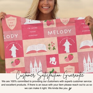 Op de afbeelding: Een roze en wit patroon deken met religieuze afbeeldingen, aardbeien en tekst. De tekst bevat "Choose the Right", "Melody" en "I'm going there someday". De deken wordt door een persoon vastgehouden.