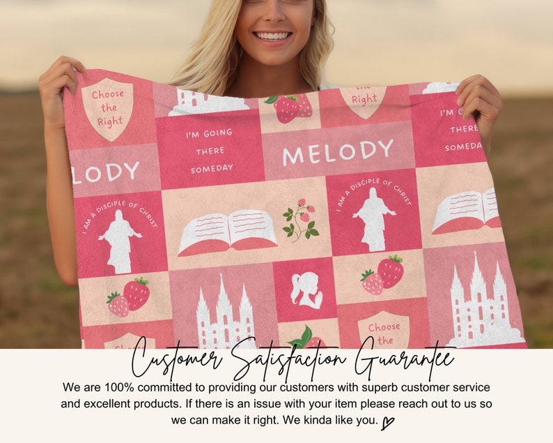 Op de afbeelding: Een roze en wit patroon deken met religieuze afbeeldingen, aardbeien en tekst. De tekst bevat "Choose the Right", "Melody" en "I'm going there someday". De deken wordt door een persoon vastgehouden.