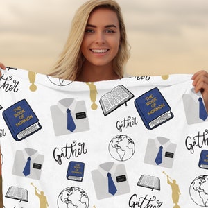 May include: White fabric with a repeating pattern of blue and gold religious symbols. The symbols include a book with the text "The Book of Mormon", a white shirt with a blue tie, a globe, and the word "Gather".
