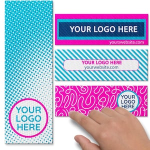 May include: A collection of colorful business labels with the text "YOUR LOGO HERE" and a website address. The labels feature various designs, including a blue and white dotted pattern, diagonal stripes, and abstract swirls. The labels are in shades of pink, blue, and white.