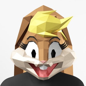 May include: A brown and yellow papercraft mask of a cartoon rabbit with large eyes and a wide smile. The mask is made of folded paper and has a 3D effect.