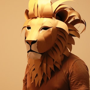 Op de afbeelding: Een persoon draagt ​​een bruin papieren mach&eacute;-leeuwenmasker. Het masker heeft een gedetailleerde manen en realistische gezichtskenmerken.