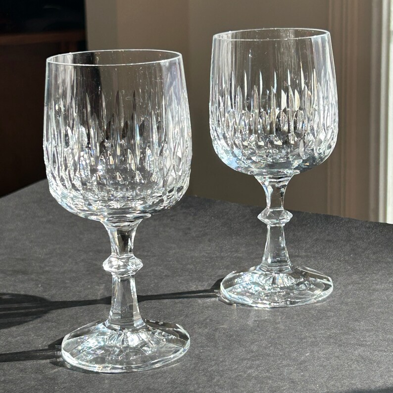 Puede incluir: Dos copas de vino de cristal transparente con un dise&ntilde;o de cristal tallado. Las copas tienen un tallo alto y una copa redonda.