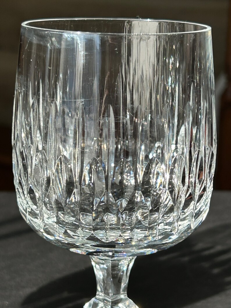 Puede incluir: Una copa de vidrio transparente con un dise&ntilde;o de cristal tallado. La copa tiene una copa ancha y un tallo alto.