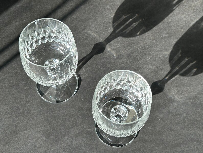 Puede incluir: Dos copas de vino de vidrio transparente con un patr&oacute;n texturizado en forma de diamante. Las copas est&aacute;n vac&iacute;as y est&aacute;n sobre una superficie gris oscuro.