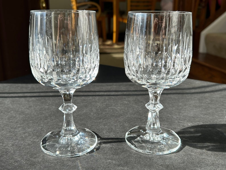 Puede incluir: Dos copas de vino de vidrio transparente con un dise&ntilde;o de vidrio cortado. Las copas tienen una copa alta y delgada y un tallo corto.