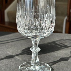 Puede incluir: Una copa de vino de cristal tallado transparente. La copa tiene un tallo alto y una base redonda.