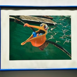 May include: A cartoon pelican with an open beak flies over a blue and green ocean with a group of small birds. The pelican is carrying three small fish in its beak.