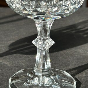 Puede incluir: Una copa de vidrio transparente con un dise&ntilde;o de cristal tallado. La copa tiene una copa ancha y un tallo alto y delgado.