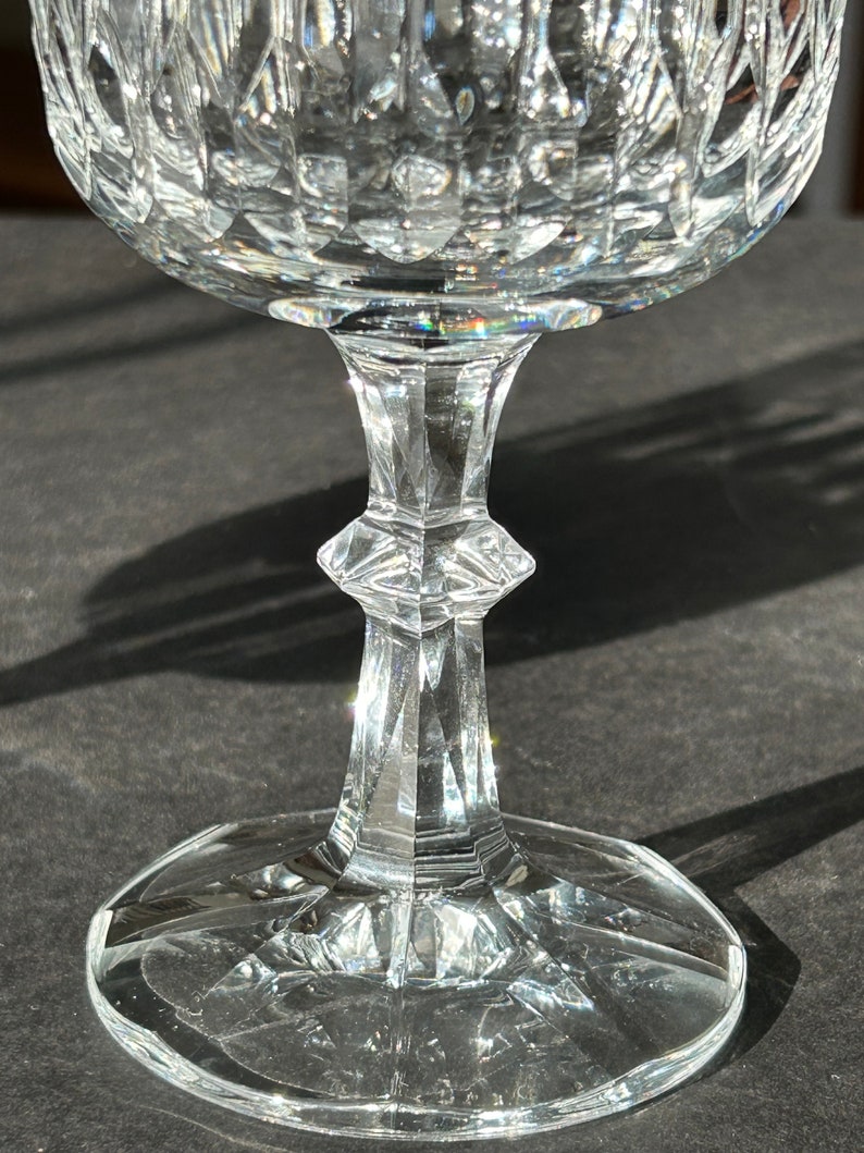 Puede incluir: Una copa de vidrio transparente con un dise&ntilde;o de cristal tallado. La copa tiene una copa ancha y un tallo alto y delgado.